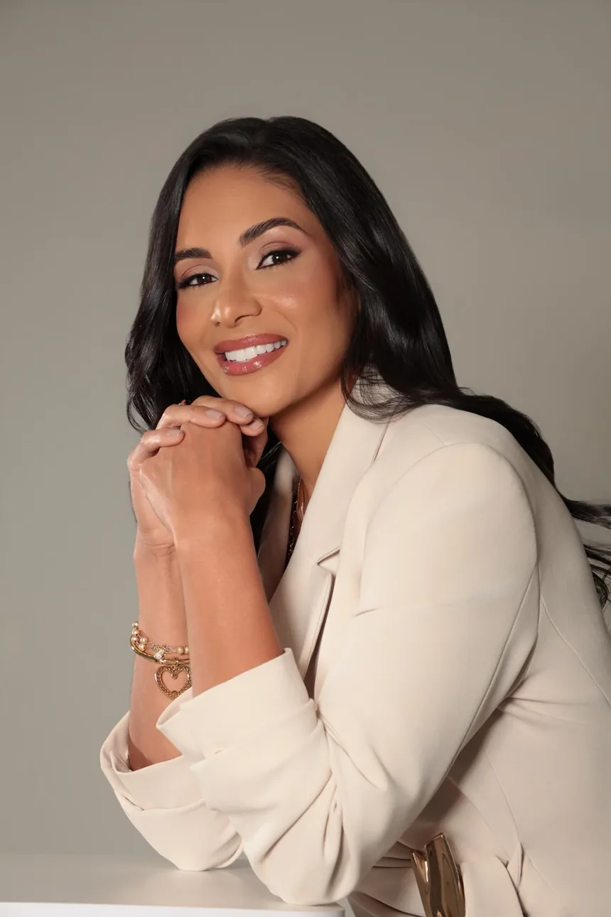 Fundadora da PODOLAF sorrindo, de blazer claro, com as mãos apoiadas sob o queixo